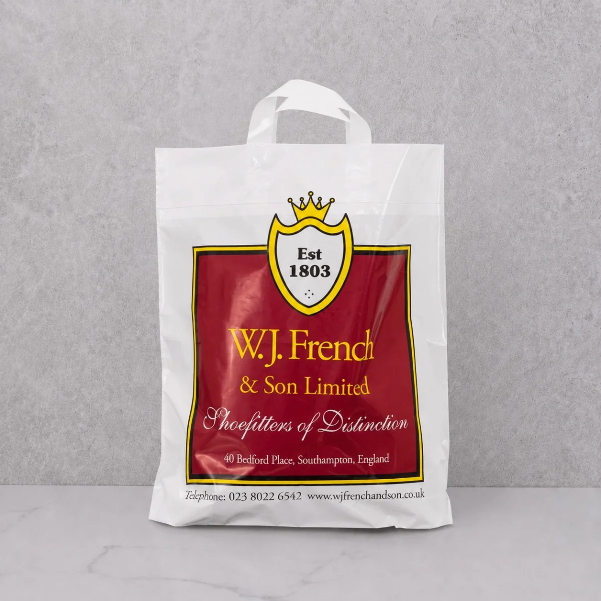 White W.J. French & Son Printed Flexiloop Plastic Bag With Red Design And White Handles