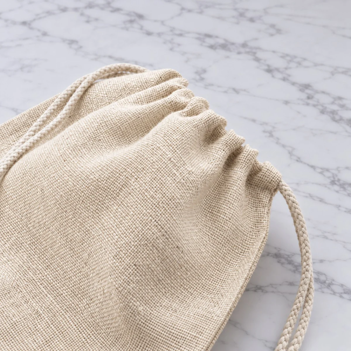Close up of a cream jute gift pouch with a gathered drawstring opening