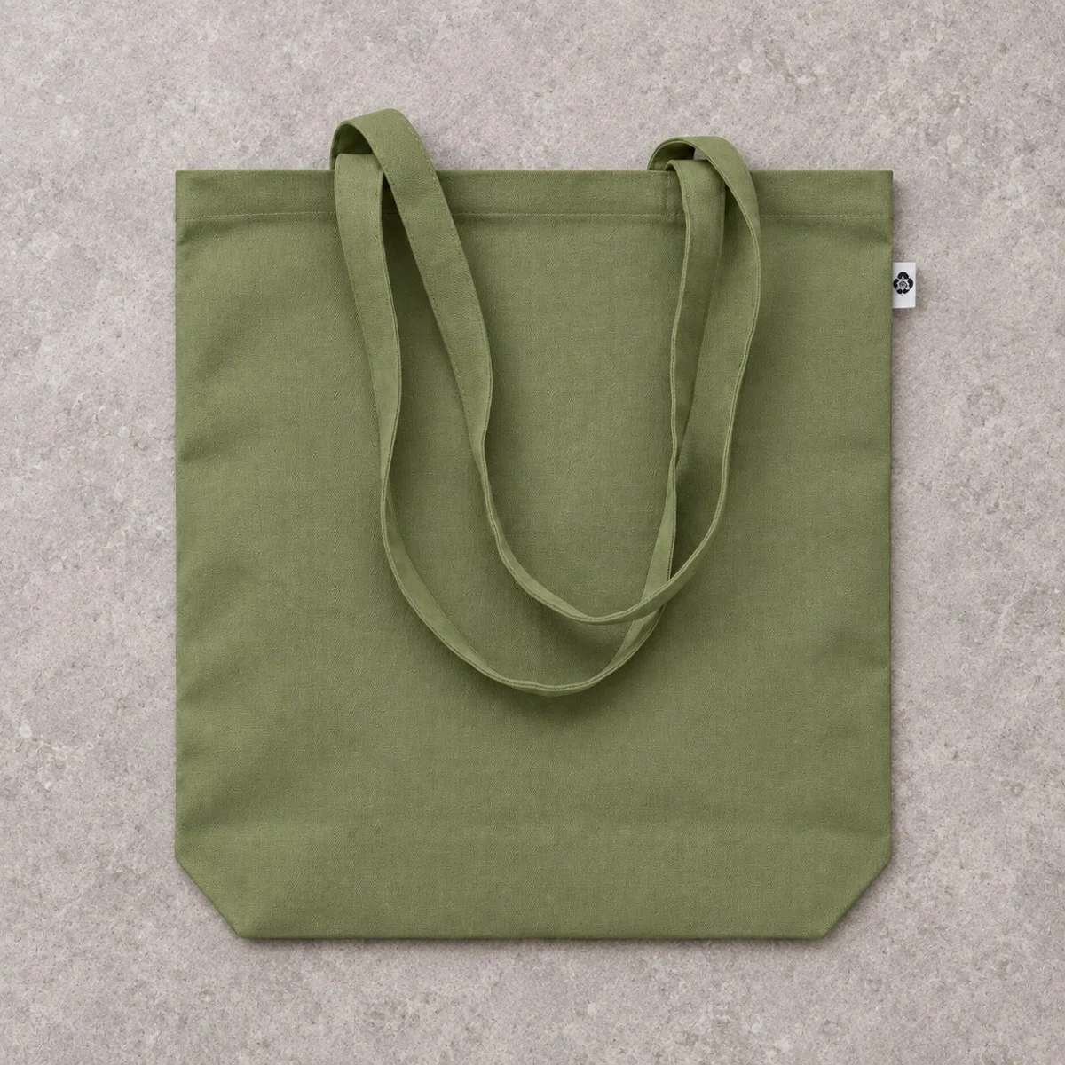 Plain Olive Green Canvas Tote Bag Laid Flat On a Textured Stone Surface